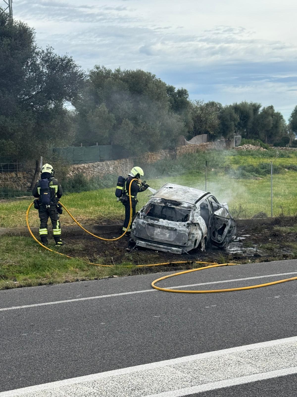 Dos bomberos, durante la extinción del incendio en el coche.
