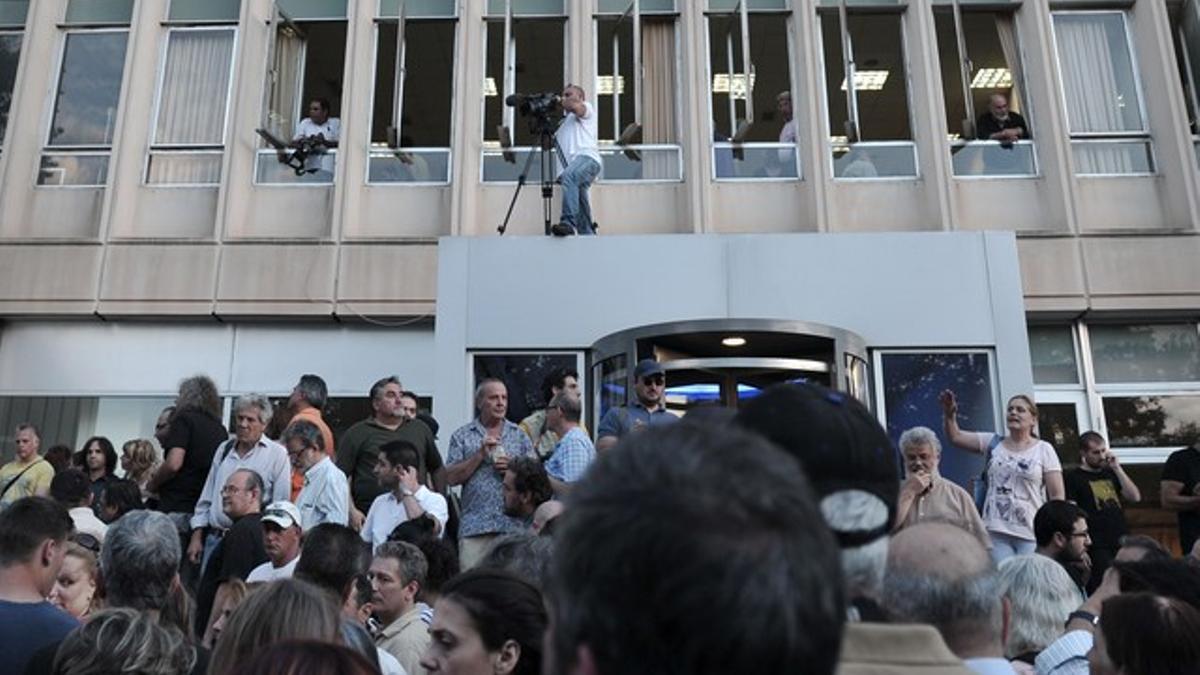 Centenares de personas se manifestan a las puertas de la sede de la radiotelevisión pública griega, este martes, en Atenas.
