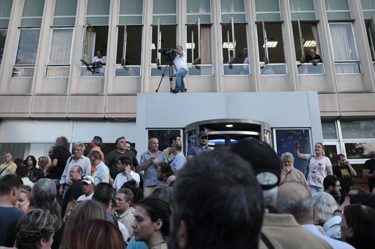 Centenars de persones es manifesten a les portes de la seu de la radiotelevisió pública grega, aquest dimarts, a Atenes.