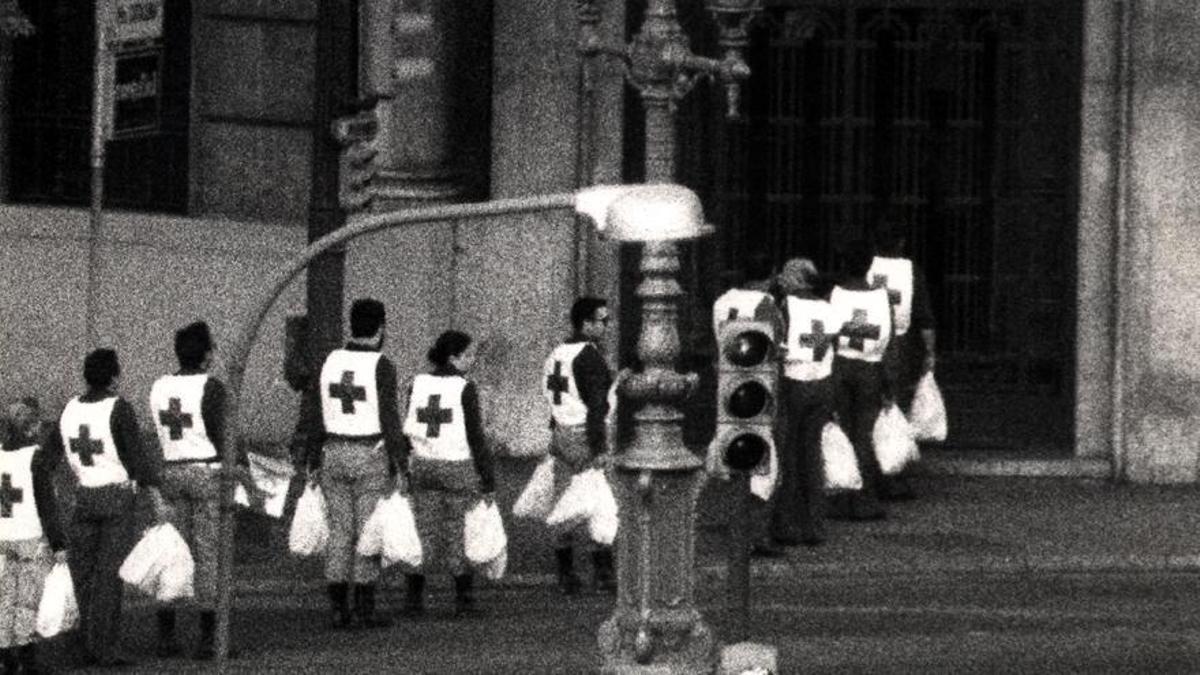 Miembros de la Cruz Roja llevan bolsas con comida a los rehenes y atracadores que siguen dentro del banco.