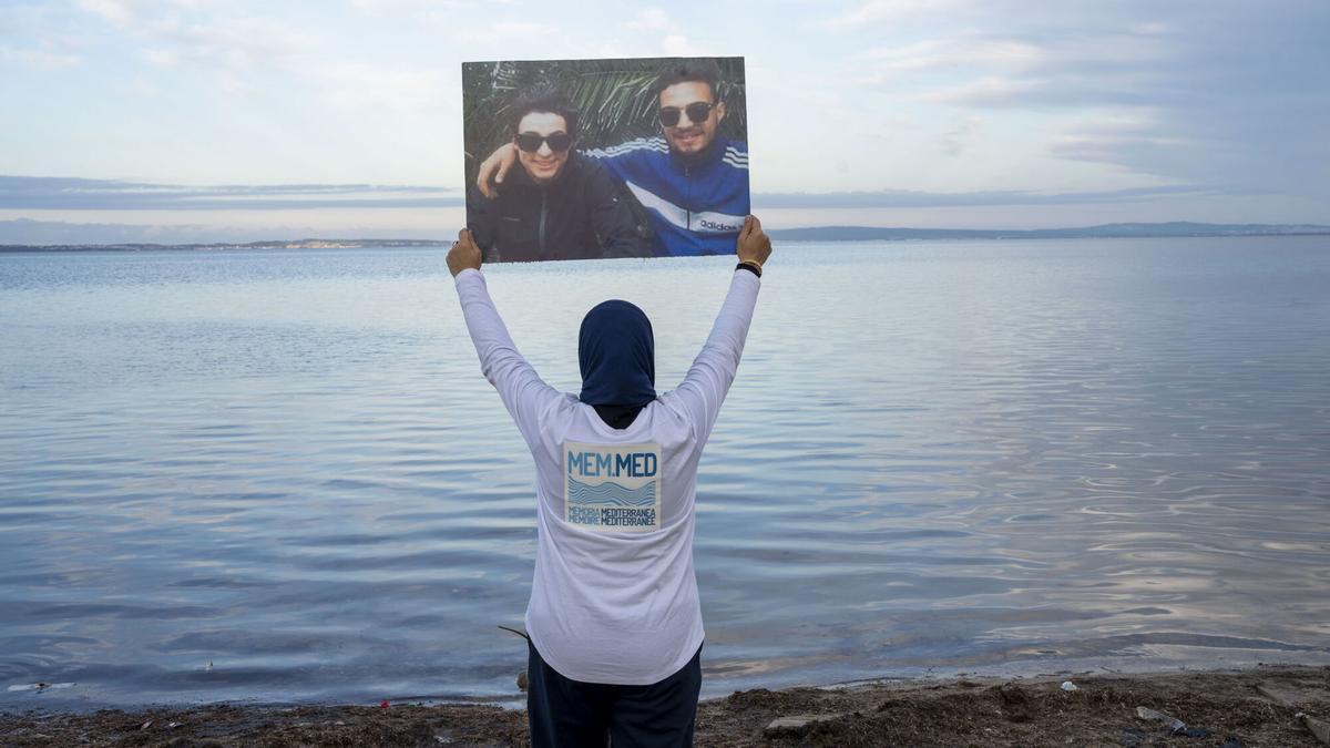Una mujer posa con los retratos de sus familares desaparecidos mientras trataban de cruzar el Mediterráneo en Menzel Bourguiba (Tunez).