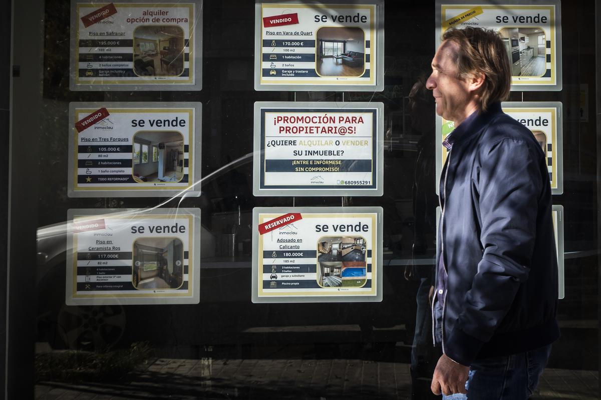 Un hombre pasa ante el escaparate de una inmobiliaria.