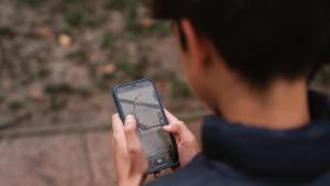 Un menor, con su teléfono móvil, en un parque de Madrid.