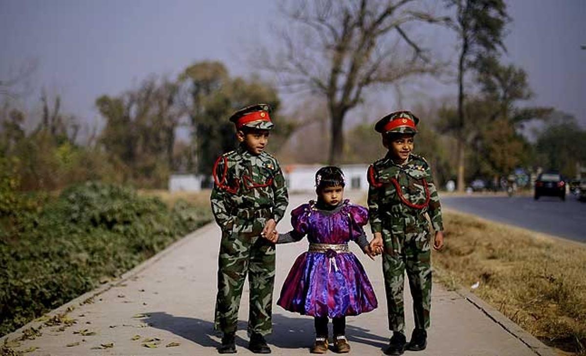 Tres germans s’agafen de la mà mentre esperen els seus pares en un barri d’Islamabad (Pakistan).