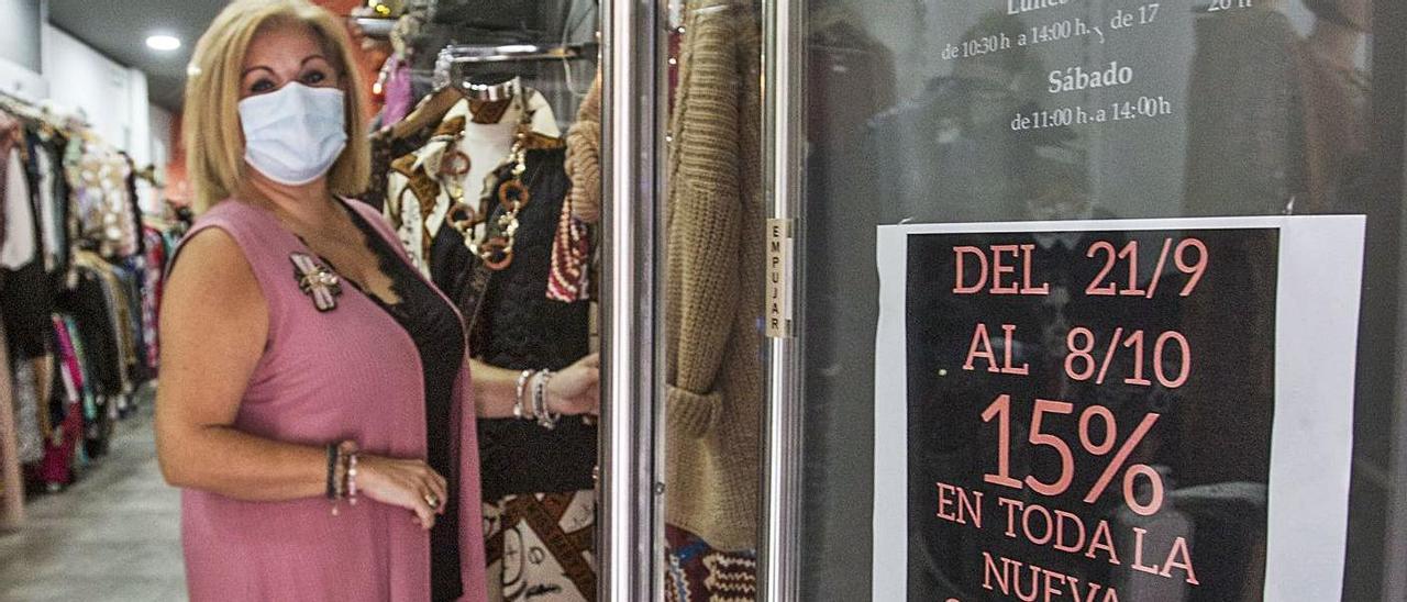 Amparo Mira, en su tienda, junto al cartel de descuento para los vacunados. |