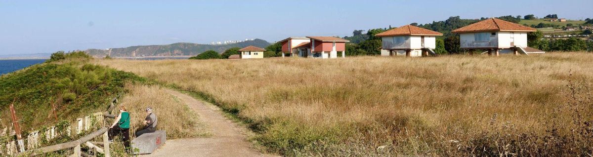 Dos mujeres se asoman a una de las viviendas abandonadas de Perlora. | Miki López