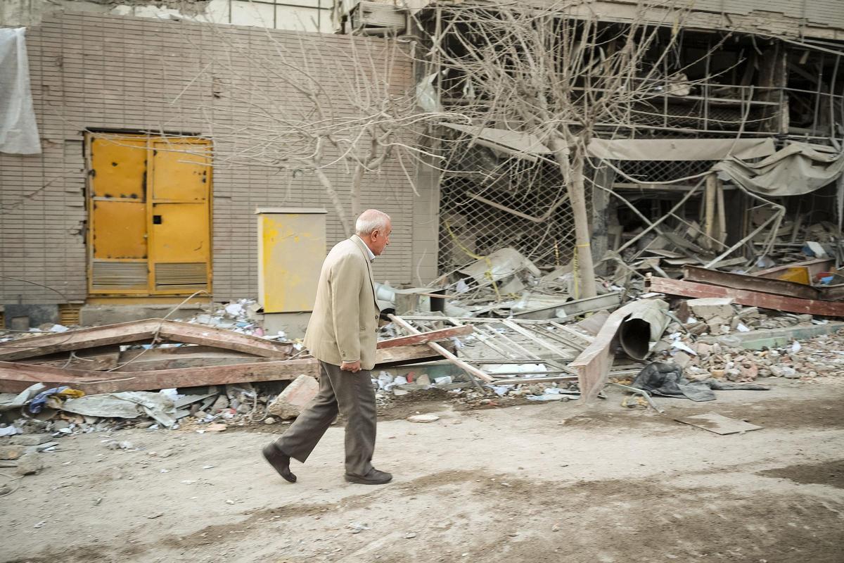 Un home camina entre les runes d'un edifici bombardejat a Teheran