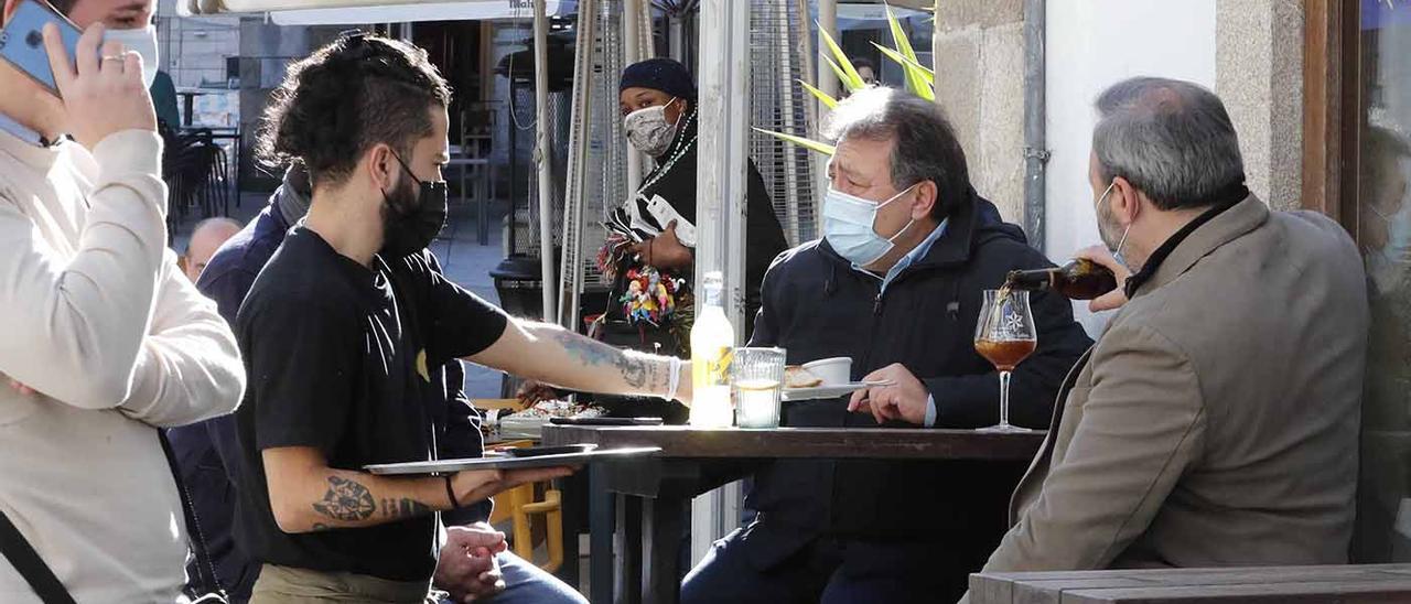 Un camarero atiende a varios clientes en una terraza del casco vello vigués