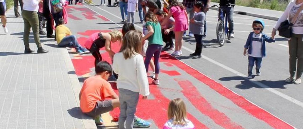 Niños pintan de rojo un tramo de la calle Italia para reivindicar más carriles bici.