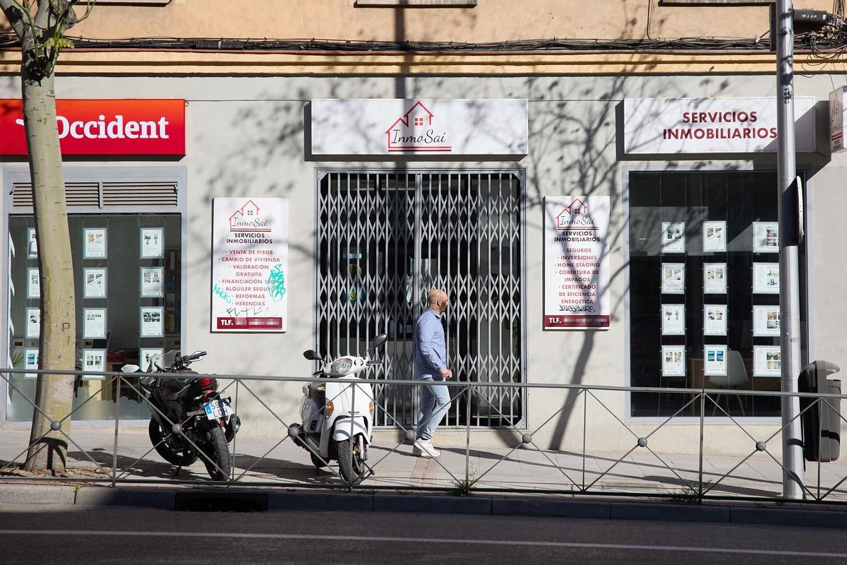 Un hombre pasa por delante de una inmobiliaria.