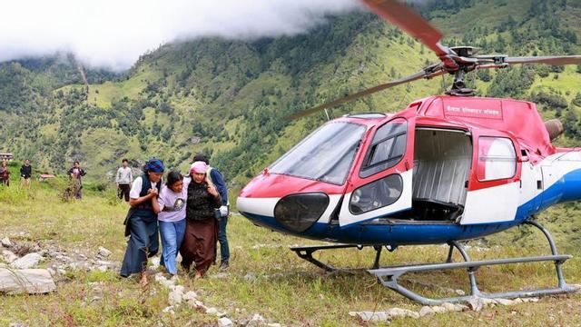 Un helicòpter per al transport de subministraments, al costat de damnificats per les inundacions, al districte nepalès de Rasuwa, ahir. | PRABIN RANABHAT / AFP