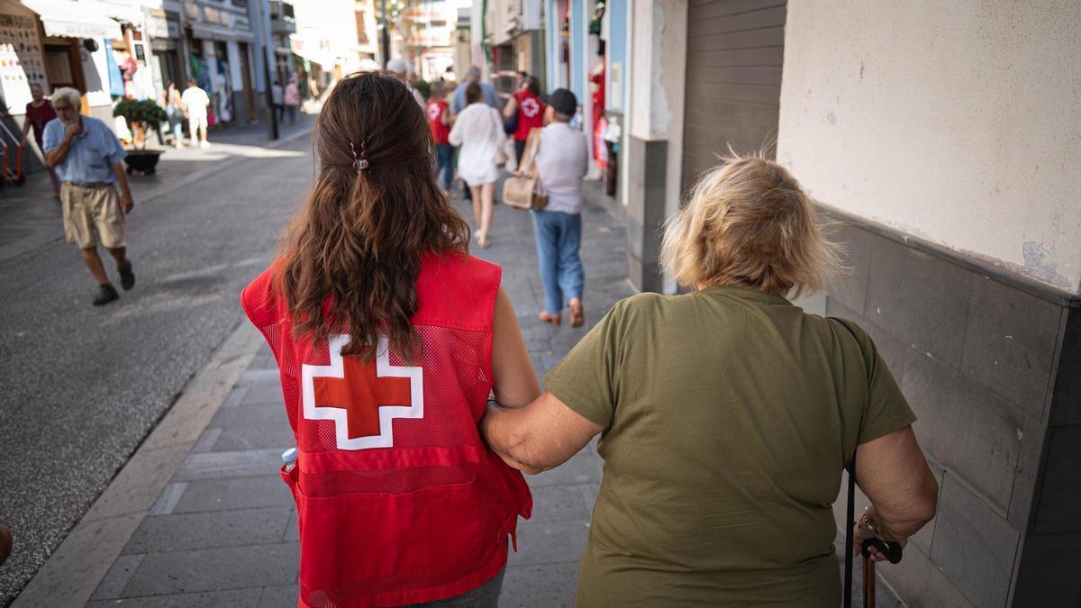 Una persona dependiente pasea acompañada de una trabajadora de Cruz Roja