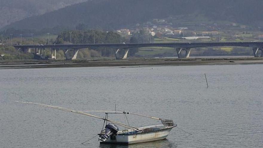 Una embarcación de marisqueo a flote. Al fondo, el puente de la autopista. / víctor echave