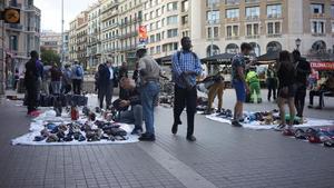 Un grupo de manteros venden sus productos a los turistas este domingo en Plaza Catalunya