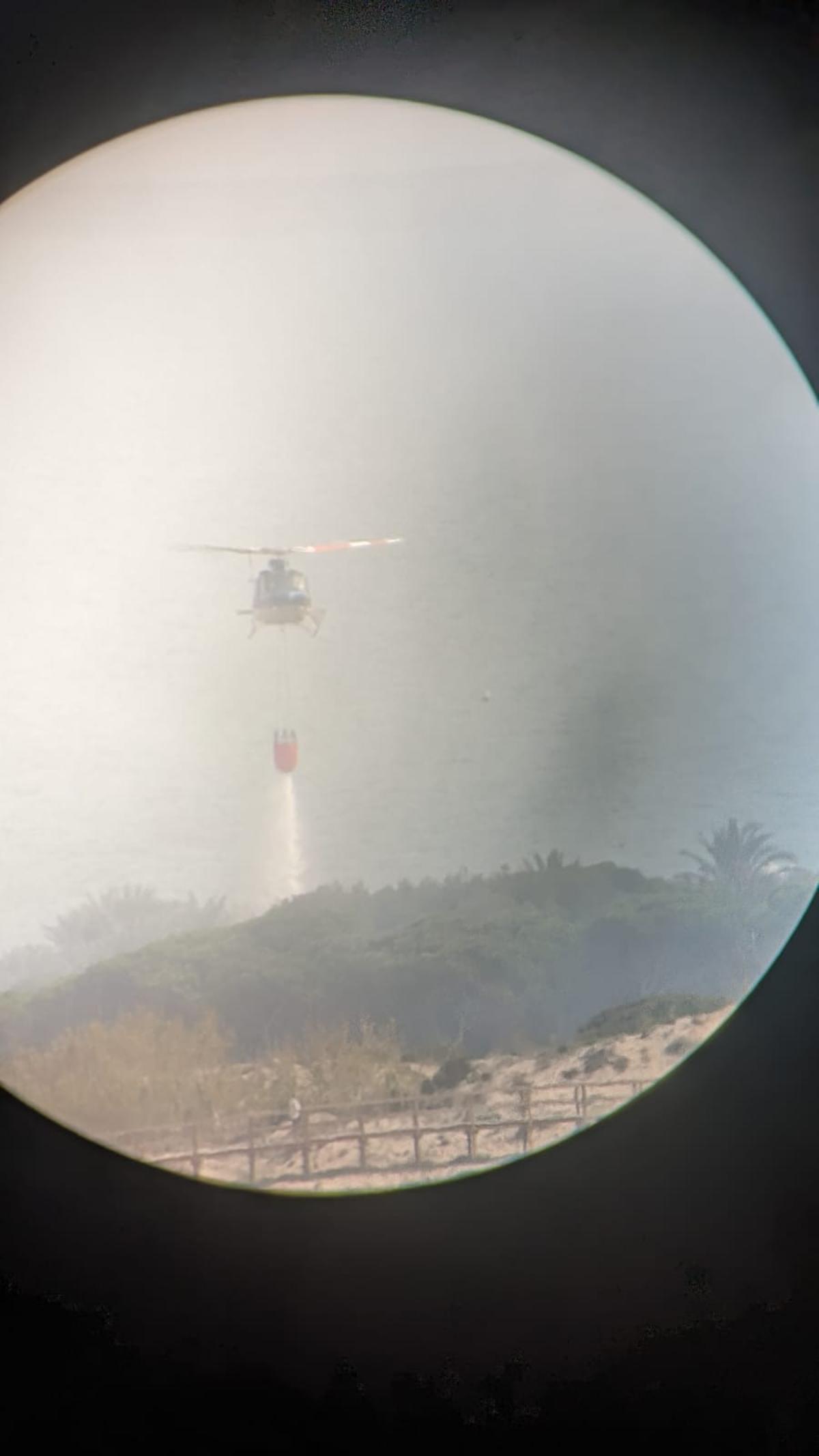 El helicóptero arrojando agua sobre la superficie en llamas