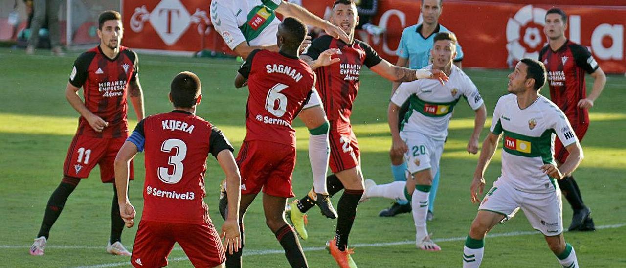 El centrocampista del Elche Manuel Sánchez queda desequilibrado tras saltar por un balón con el central del Mirandés Sagnan.