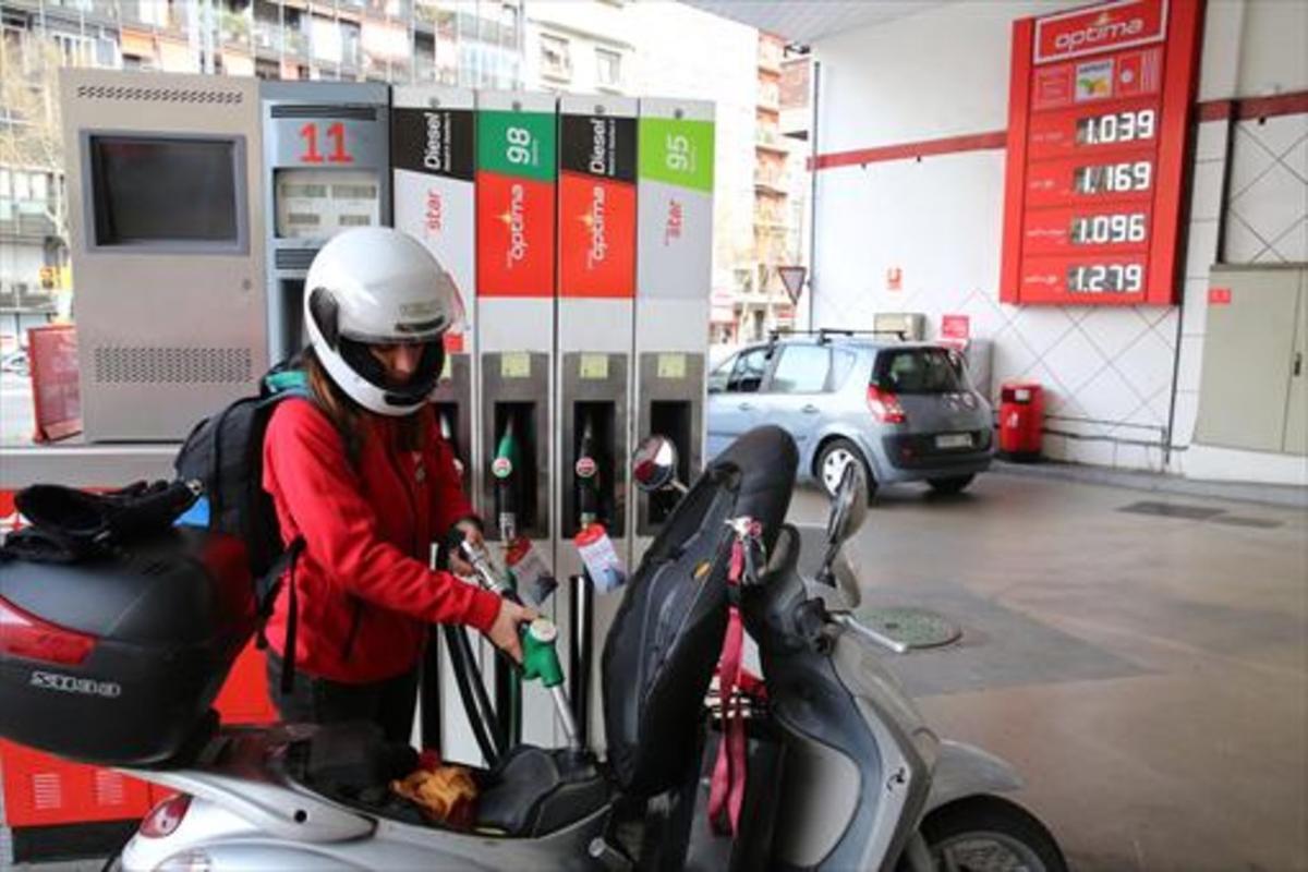 Una joven reposta carburante para su moto en una gasolinera del Paral·lel, el martes.