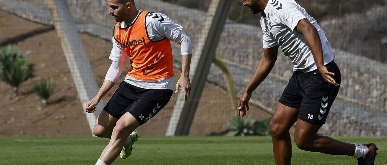 Kirian Rodríguez golpea el balón perseguido por Sidnei durante el entrenamiento de ayer en Barranco Seco. | | LP/DLP