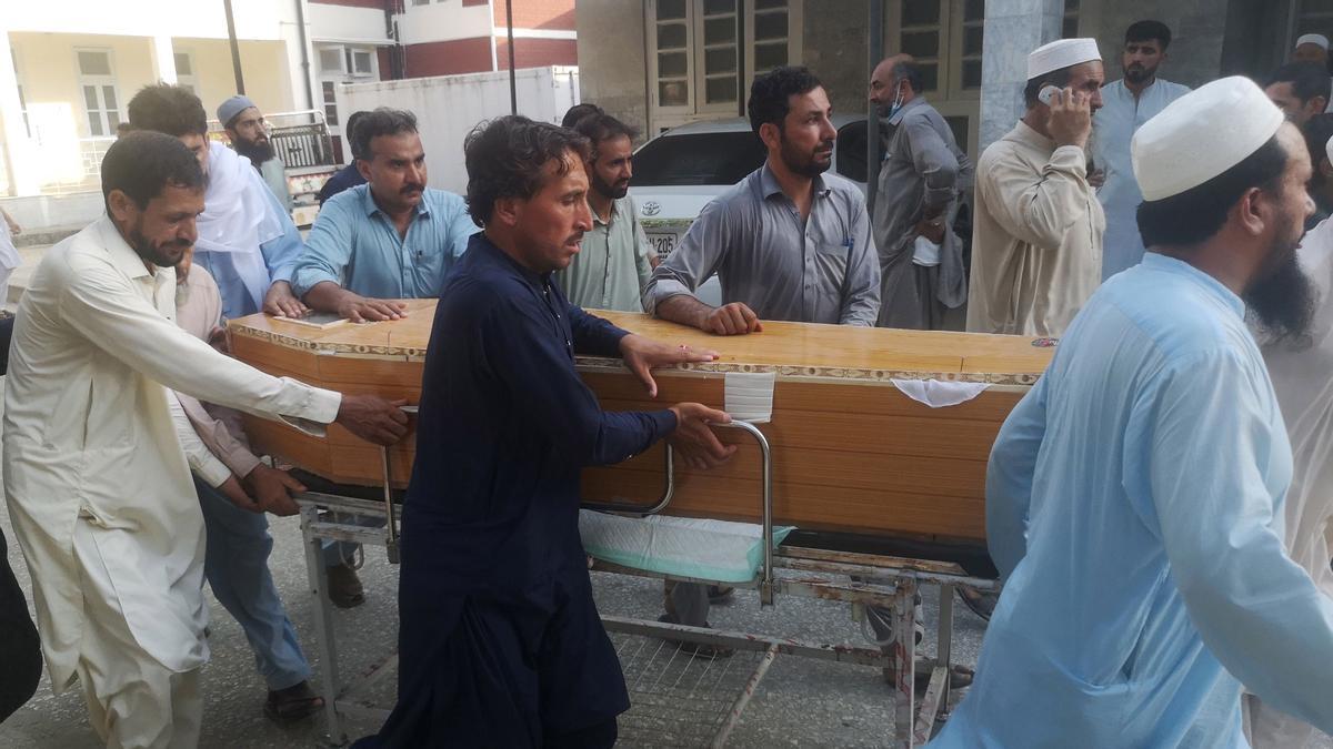 Varios hombres mueven ataúdes frente a un hospital.
