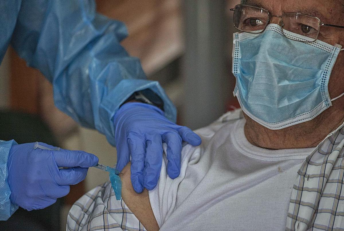 Un sanitario dispensa la vacuna contra el COVID a un anciano en Allariz. | // BRAIS LORENZO