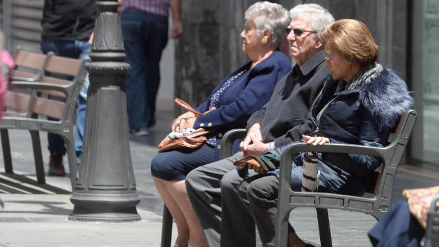 Jubilados canarios descansan en un banco.