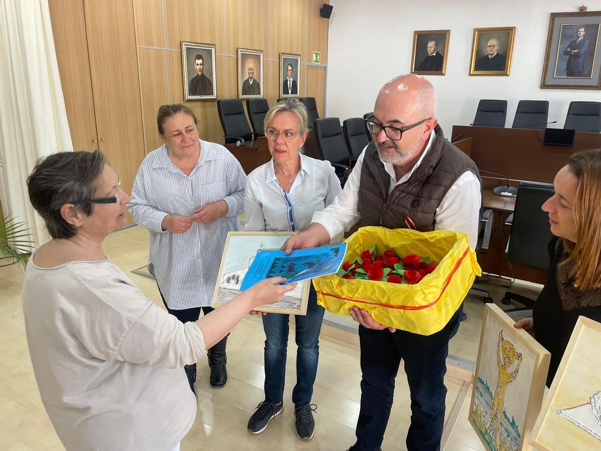 Una mujer entrega la revista e imanes de rosas al alcalde