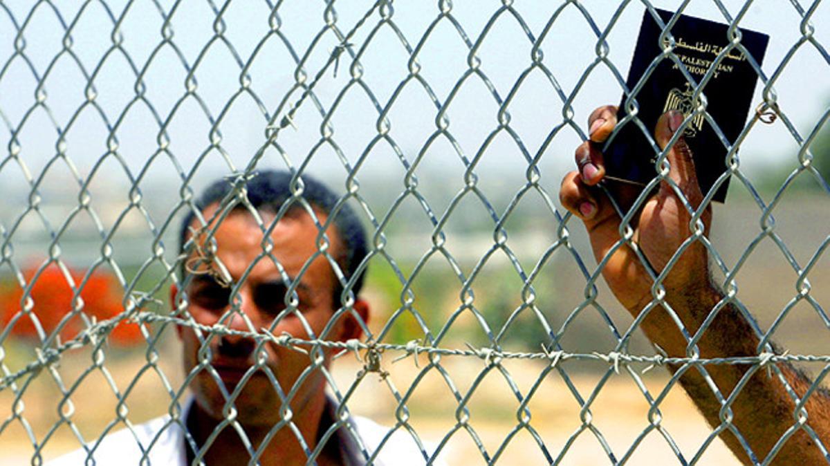 Palestins, amb el passaport a la mà, darrere d’una tanca a l’espera de travessar el pas fronterer de Rafah entre Egipte i Gaza.
