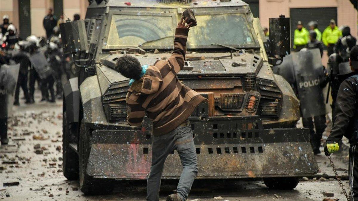 Un manifestante lanza un objeto contra un vehículo policial en una protesta contra el Gobierno de Lenin Moreno, este viernes, en Quito.