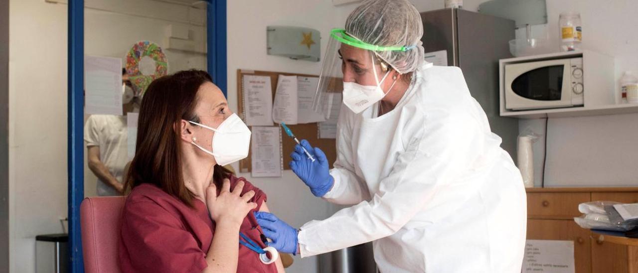 Una sanitaria vacuna a una mujer.