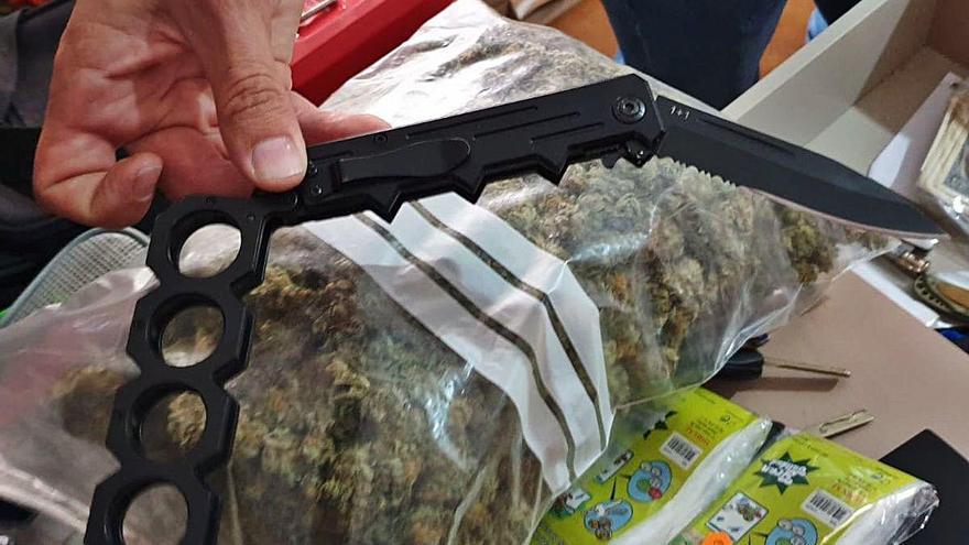 Una navaja con puño americano y debajo, una bolsa de marihuana.