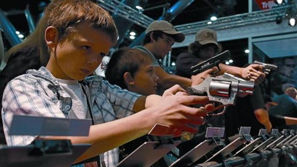 Unos niños prueban unas pistolas durante la celebración de la convención de la NRA, en Houston. /