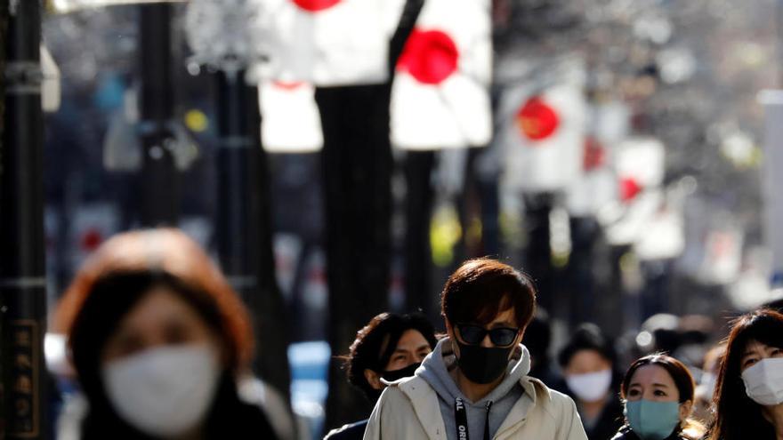 Peatones caminan con mascarillas en el centro de Tokio