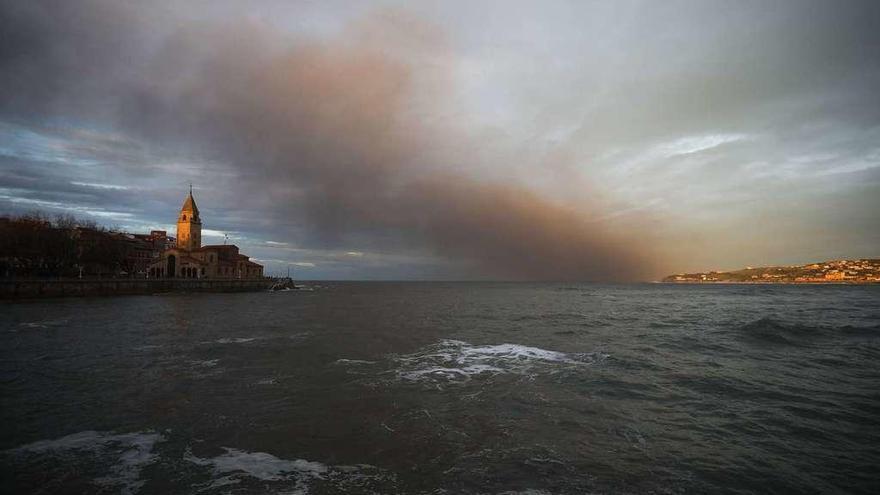 La nube de humo del incendio pasa sobre la bahía de la playa de San Lorenzo.