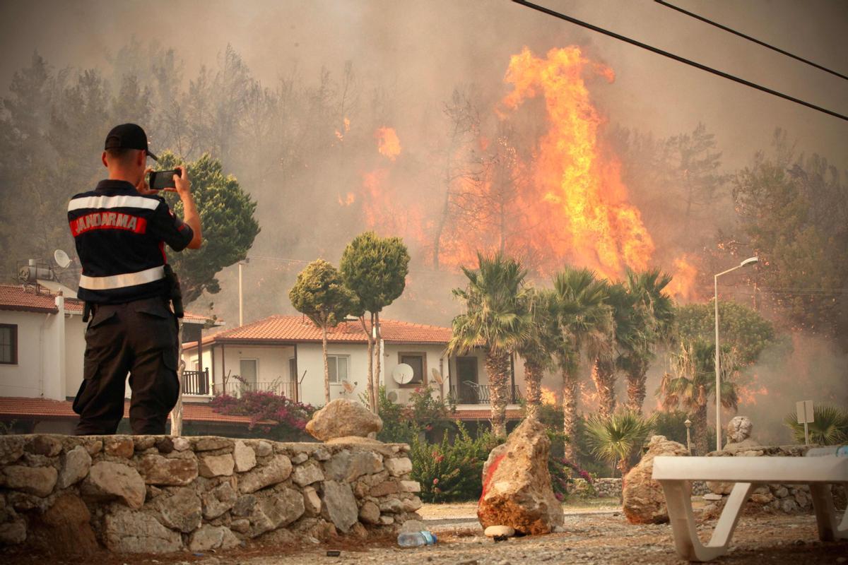 Un bombero toma fotos del fuego en la ciudad costera de Oren, cerca de Milas, en Turquía.