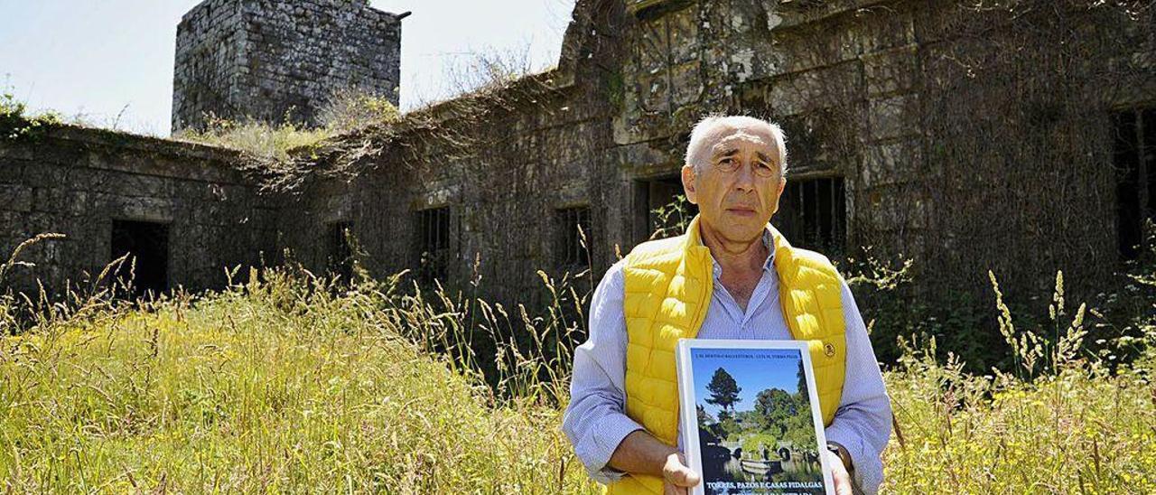 El investigador Luis Ferro, ayer, con la monografía ante A Torre y el pazo de Guimarei.