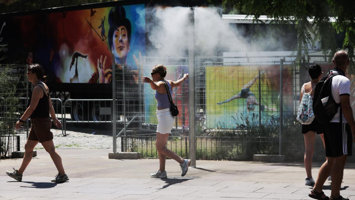 BARCELONA 15/07/2022 Ola de calor Unos turistas intentan refrescarse en unos vaporizadores de agua fresca instalados en los refugios climáticos del Passeig Joan de Borbó, en la Barceloneta FOTO de FERRAN NADEU