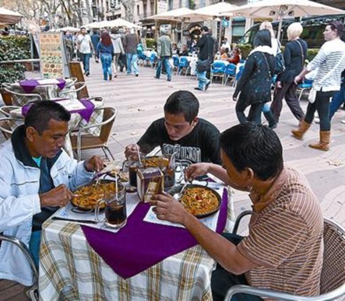 Turistes hondurenys mengen una paella a la Rambla, ahir. Turistes hondurenys mengen una paella a la Rambla, ahir.
