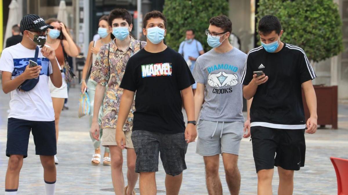 Jóvenes con mascarilla caminan por una calle de Cartagena.