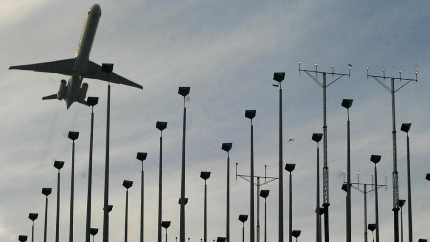 Un avión sobrevuela balizas del sistema antiniebla anterior del aeropuerto de Asturias.