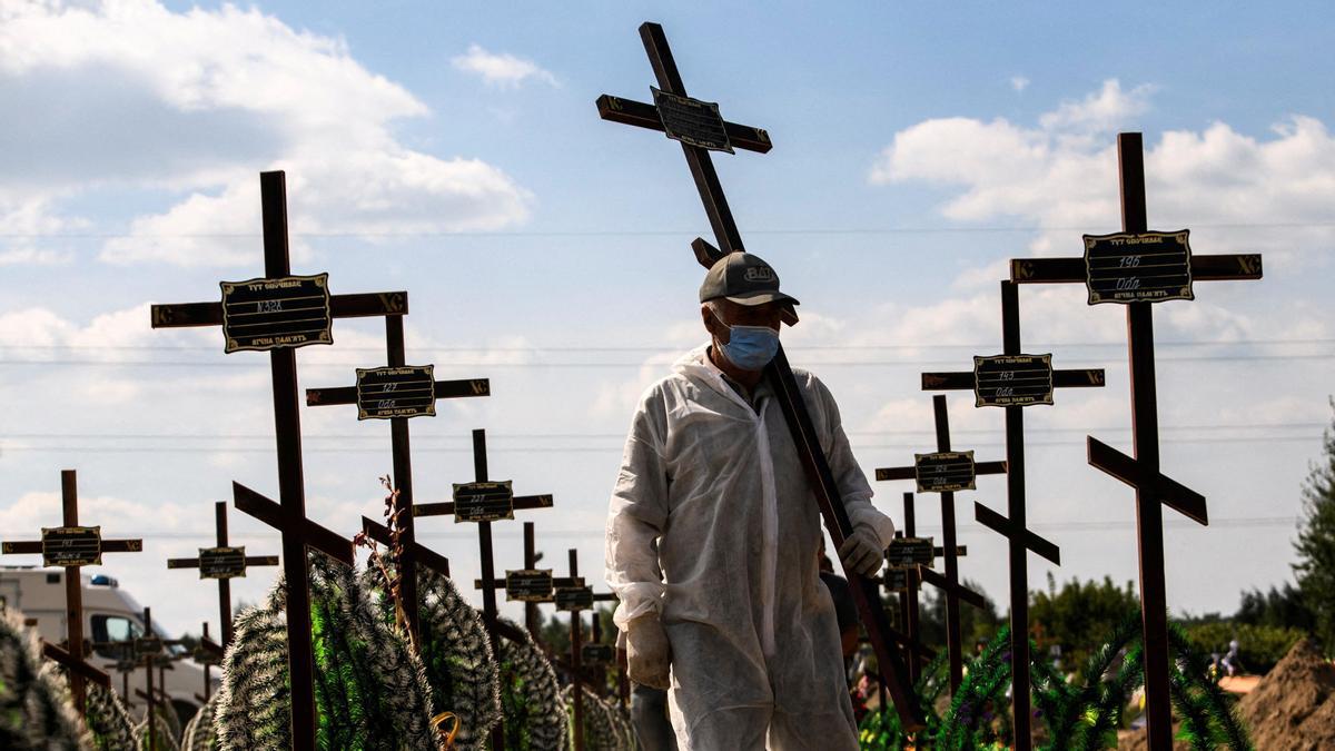 Un voluntario porta una cruz para una de las tumba de víctimas de ataques rusos en Bucha (Ucrania).
