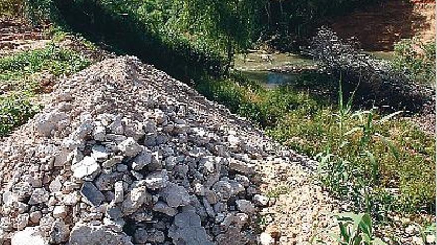 Derribos y otros residuos han sido vertidos en una parcela que dista pocos metros del río.