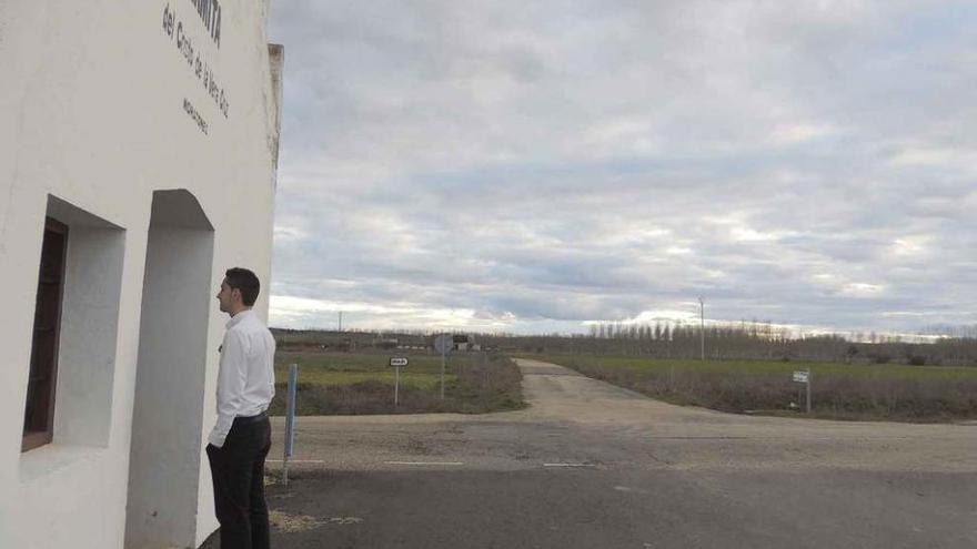 Un joven a las puertas de la ermita, al fondo el camino .