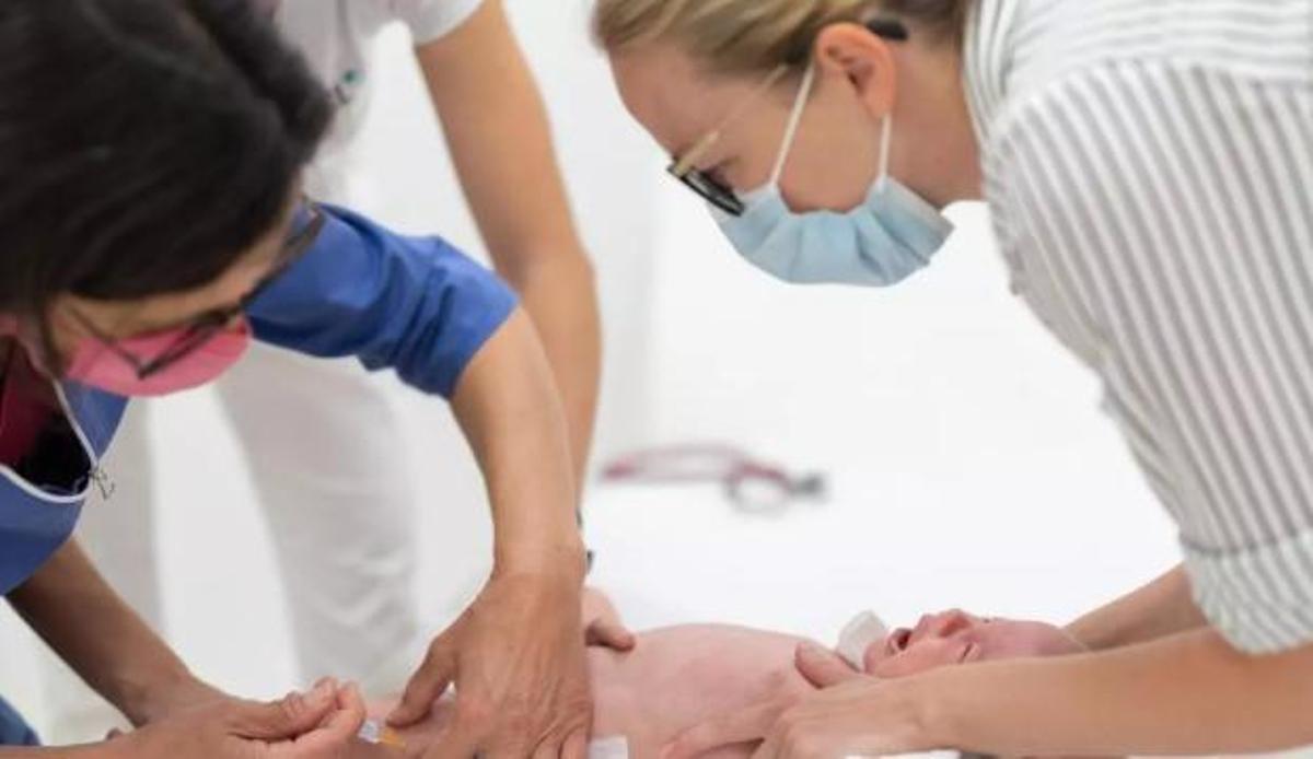 Una infermera administra una vacuna a un nadó