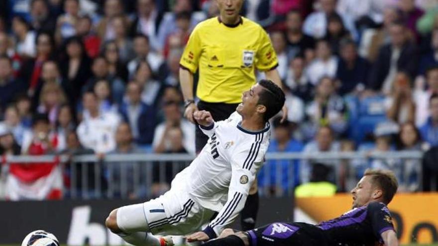 Ebert, del Valladolid, derriba a Cristiano Ronaldo, ayer, en el Santiago Bernabéu. // Susana Vera