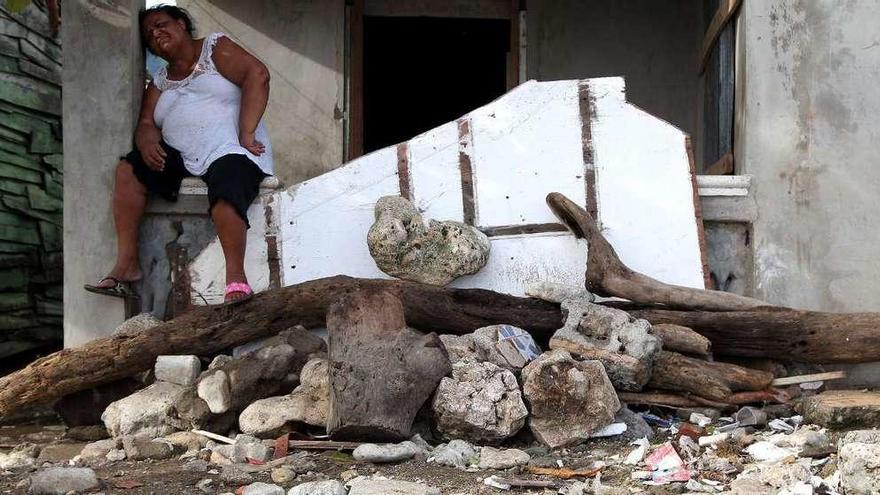 Una mujer descansa tras retirar escombros de su casa en República Dominicana. // Reuters