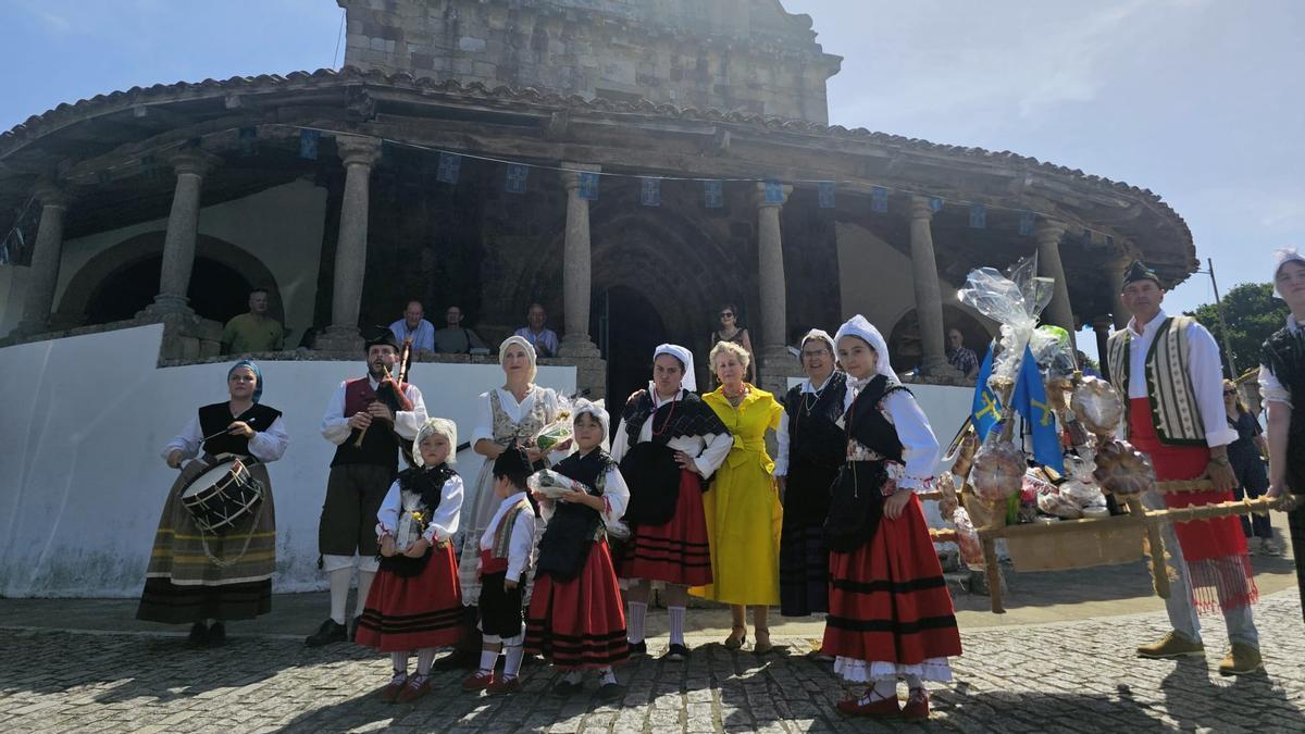 La galardonada, de amarillo, ante la iglesia de Amandi, con algunos de los participantes en la procesión, y el ramo, a la derecha de la imagen.