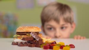 Un niño observa una mesa con comida basura.