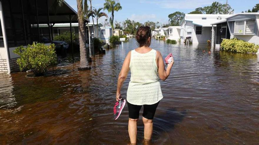 Una mujer camina por una calle anegada de la ciudad de Naples, en Florida. // Reuters