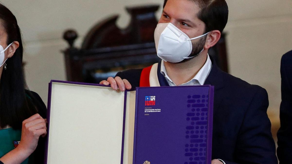 El presidente de Chile, Gabriel Boric, sostiene un ejemplar de la propuesta de Constitución.