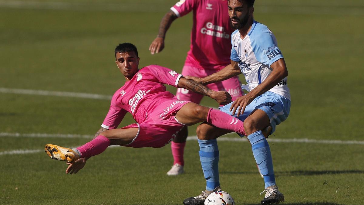 El defensa del Málaga Juande (d) zancadillea al centrocampista francés Enzo Loiodice, de Las Palmas, durante el partido de la jornada quinta de liga de Segunda División entre Málaga y Las Palmas, este domingo en el Estadio de la Rosaleda en Málaga.